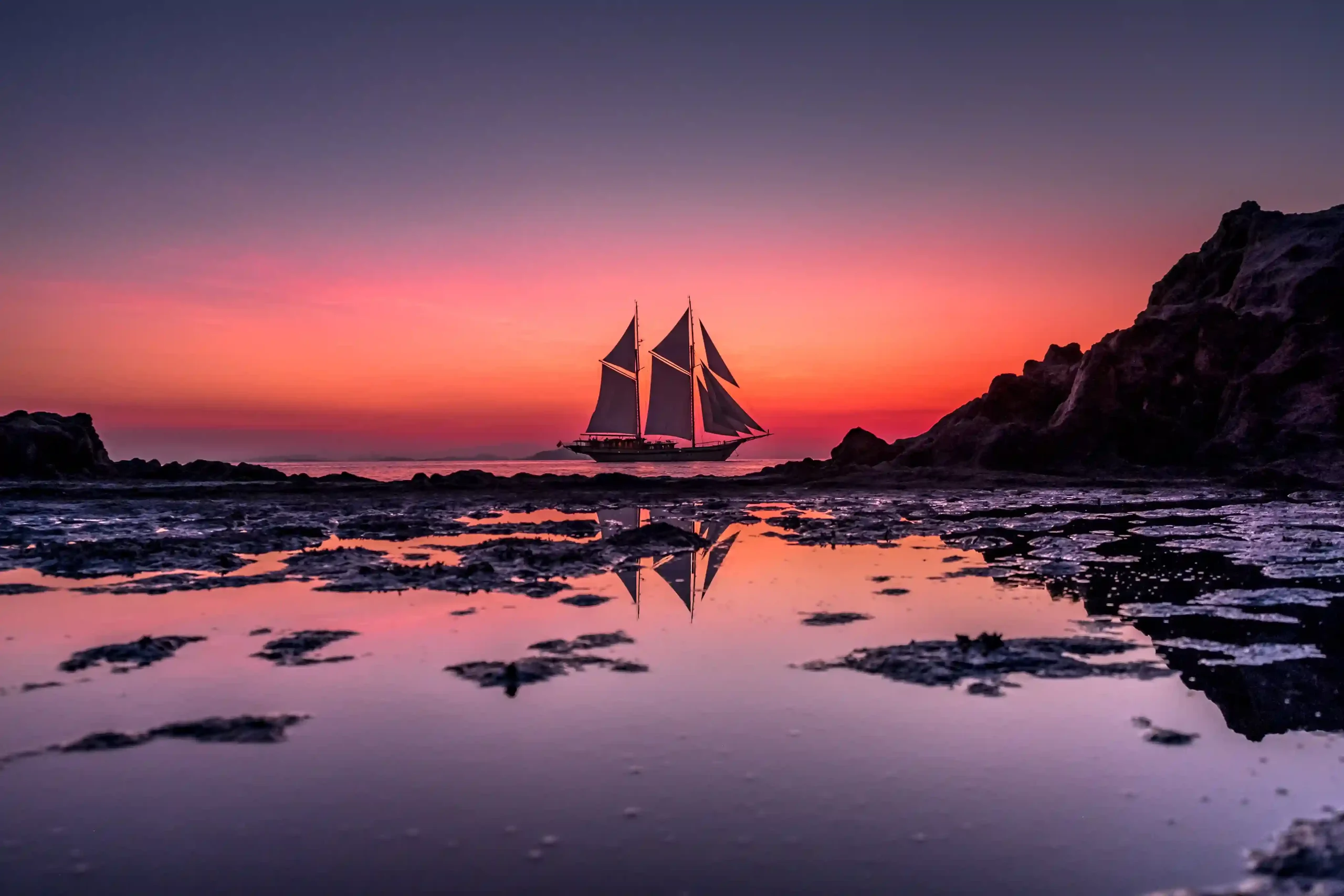 A luxury phinisi under sail at sunset in Indonesian waters